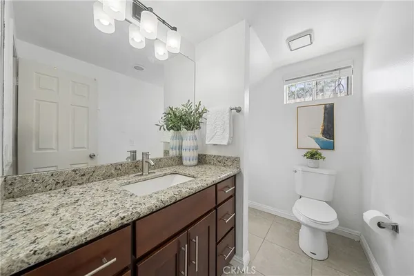 a bathroom with a granite countertop sink a toilet and mirror