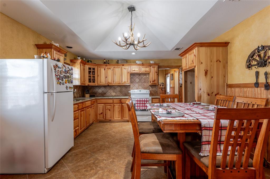 794 West Antelope Road, Unit 1 Windthorst, TX 76389 - Photo 13 of 40 a kitchen with stainless steel appliances granite countertop a refrigerator a sink dishwasher a dining table and chairs with wooden floor