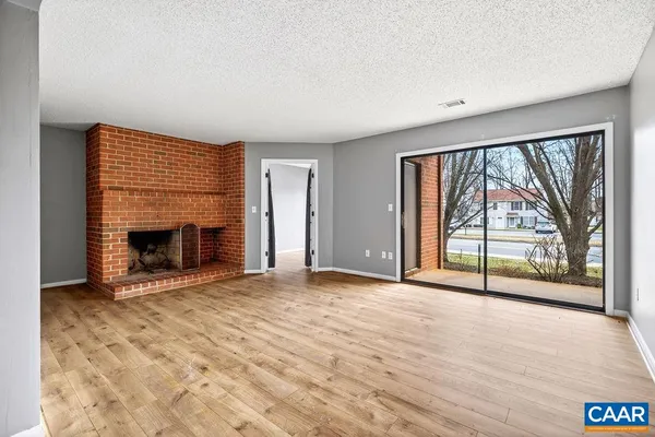 an empty room with large windows and a fireplace