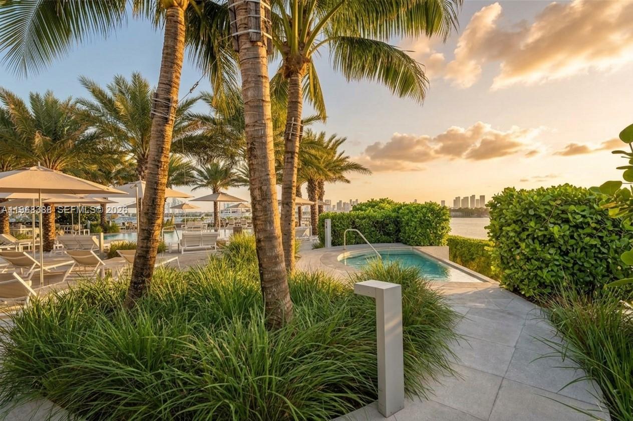 450 Alton Road, Unit 1202 Miami Beach, FL 33139 - Photo 37 of 68 a view of swimming pool with a table and chairs under palm trees