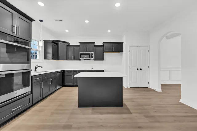 a open kitchen with stainless steel appliances kitchen island granite countertop a stove a sink and a refrigerator