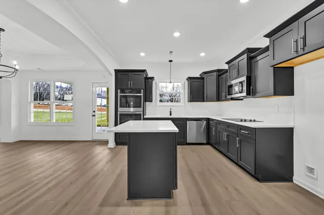 a large kitchen with stainless steel appliances kitchen island granite countertop a large counter top and wooden floors