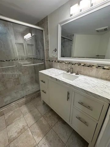 a bathroom with a double vanity sink mirror and shower
