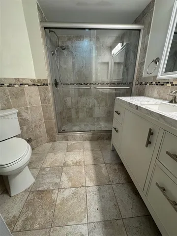 a bathroom with a granite countertop shower a toilet and a sink