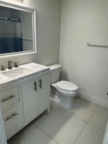 a bathroom with a granite countertop toilet sink and mirror