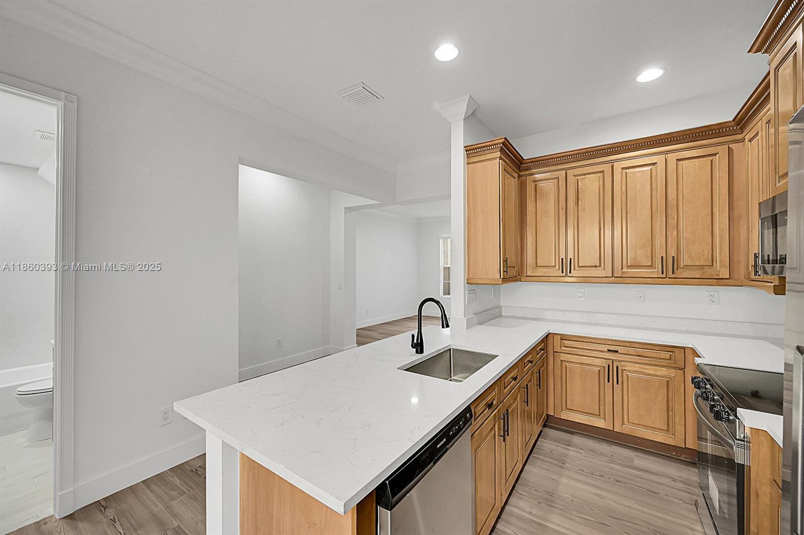 8305 Northwest 8th Terrace Boca Raton, FL 33487 - Photo 8 of 39 a kitchen with a sink dishwasher a stove and white cabinets with wooden floor