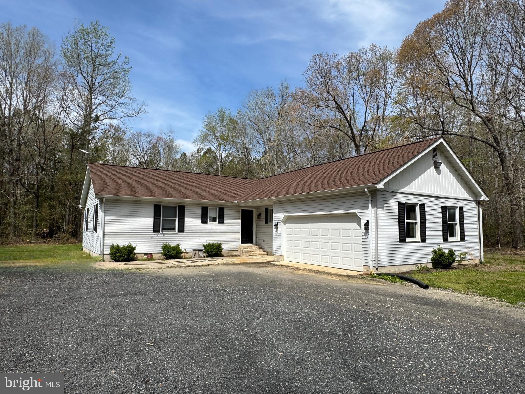 a front view of house with yard and trees in the background