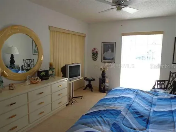 a bedroom with a bed a dresser and flowerpot