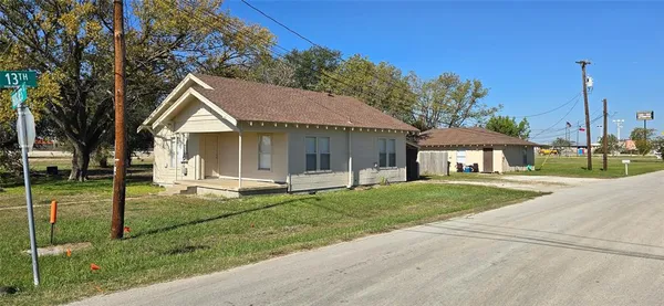 a view of a house with a yard and large tree