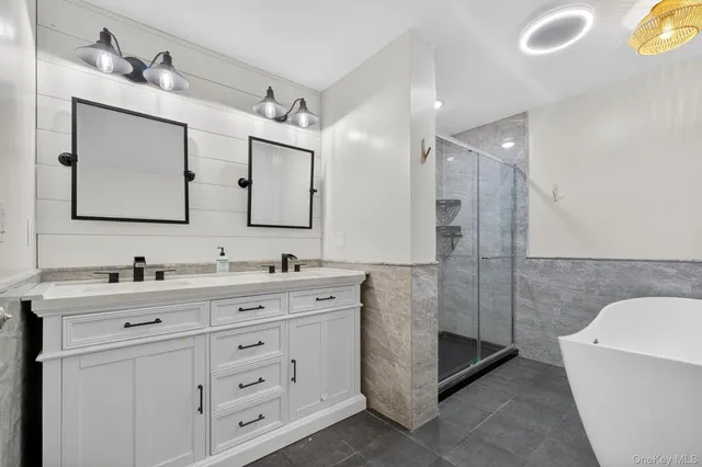 a bathroom with a double vanity sink mirror and bathtub
