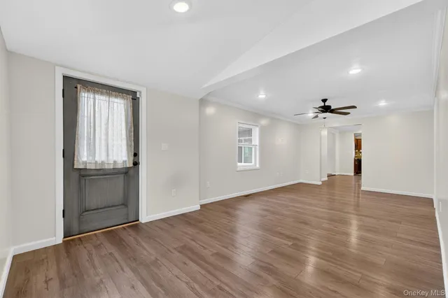 an empty room with wooden floor chandelier and windows