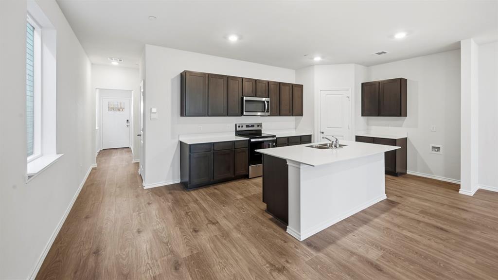 206 Redwood Road Princeton, TX 75407 - Photo 27 of 40 a kitchen with stainless steel appliances granite countertop a stove top oven a sink a refrigerator and white cabinets with wooden floor