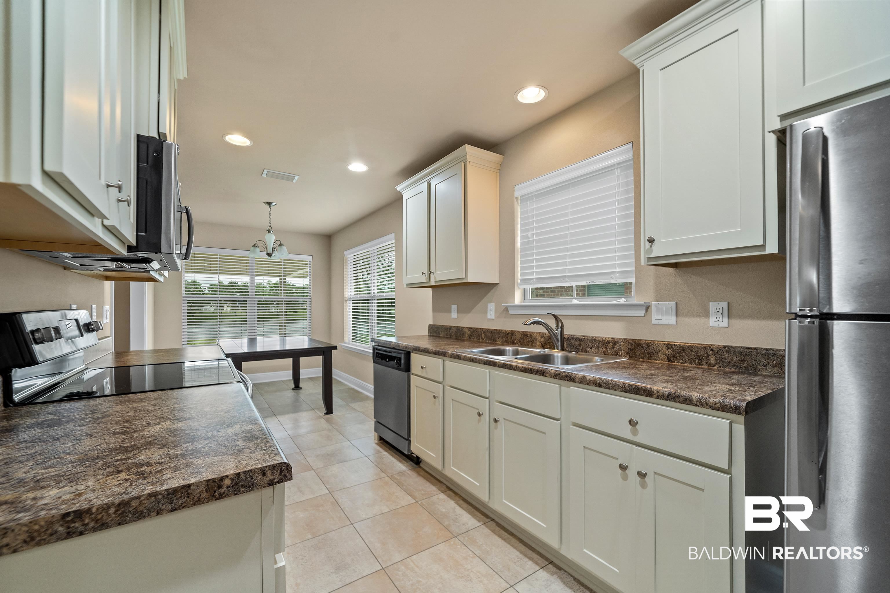 22631 Lake South Drive Foley, AL 36535 - Photo 8 of 25 Kitchen featuring white cabinets, light tile patterned floors, stainless steel appliances, decorative light fixtures, and sink