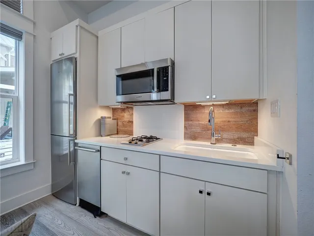 a kitchen with stainless steel appliances granite countertop white cabinets a refrigerator a sink and a stove