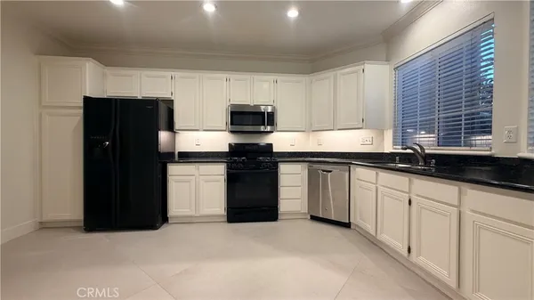 a kitchen with granite countertop white cabinets and refrigerator
