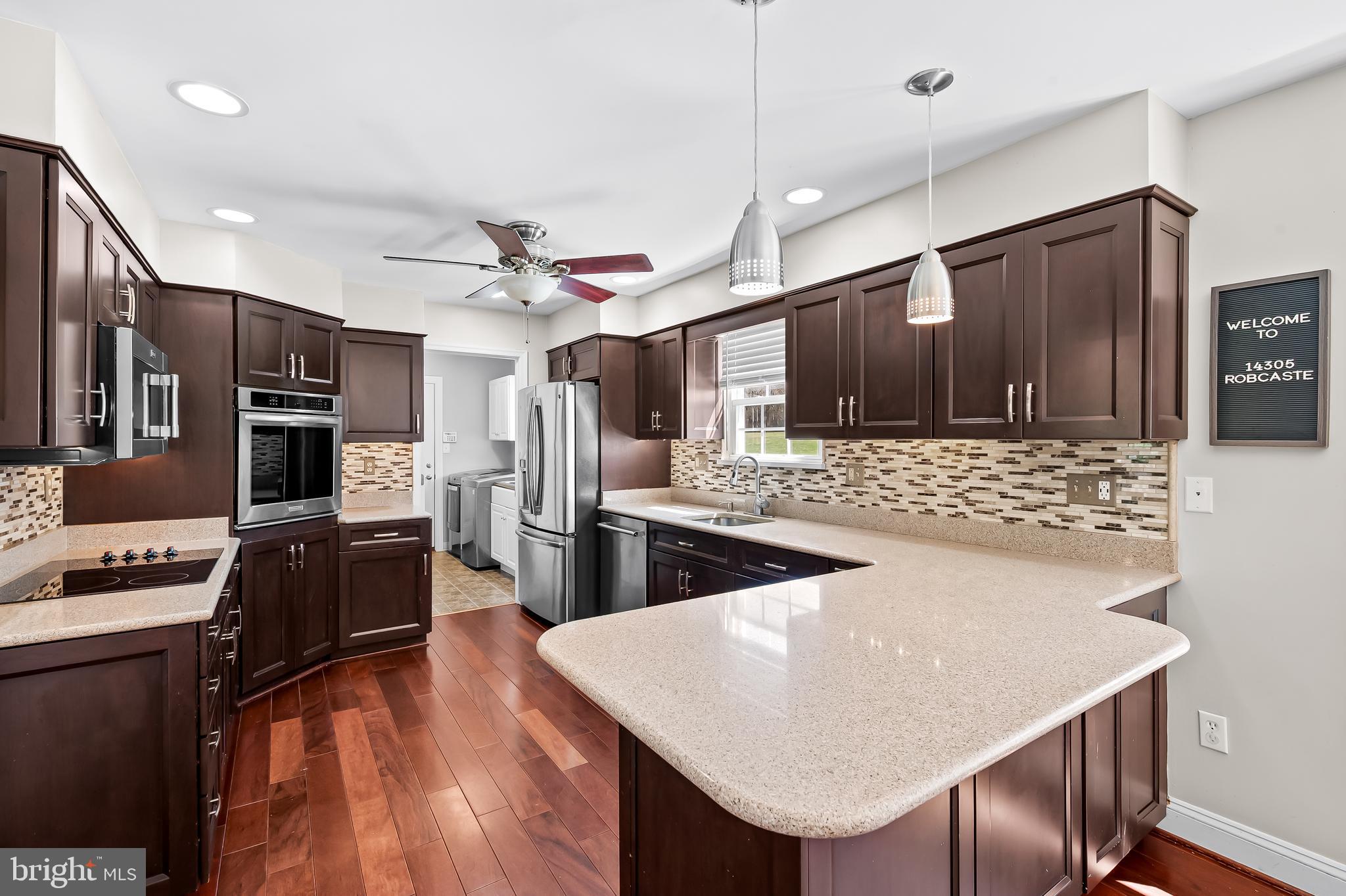 14305 Robcaste Road Phoenix, MD 21131 - Photo 14 of 53 a kitchen with stainless steel appliances kitchen island granite countertop a refrigerator a stove and a sink with wooden floor