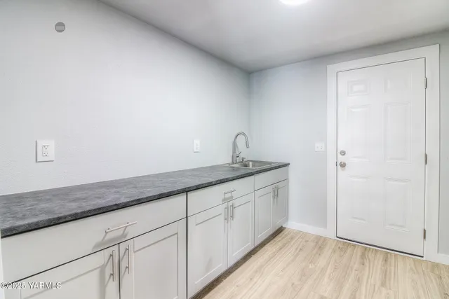 a hallway with granite countertop white cabinets and a wooden floor