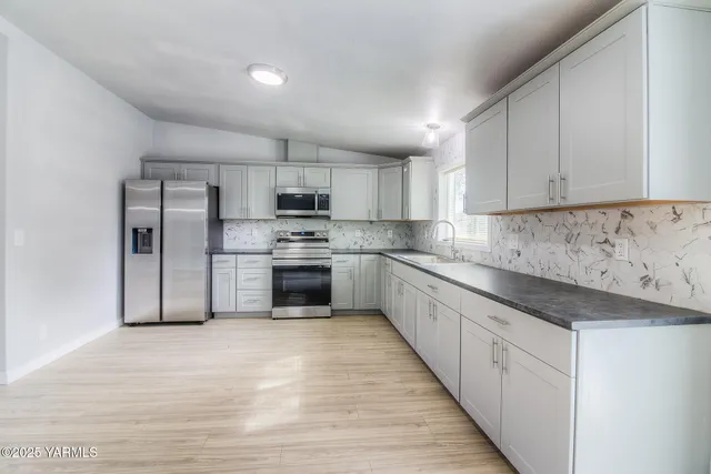 a kitchen with stainless steel appliances granite countertop a refrigerator sink and cabinets