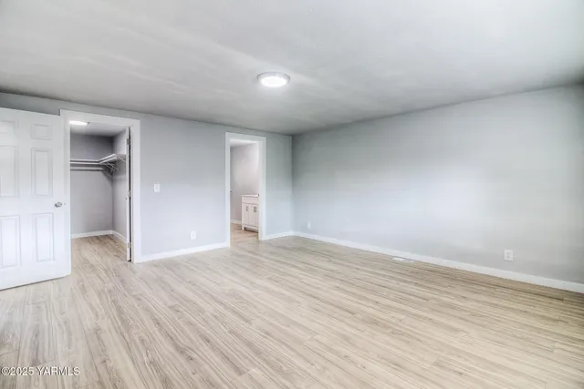 a view of an empty room with wooden floor and closet