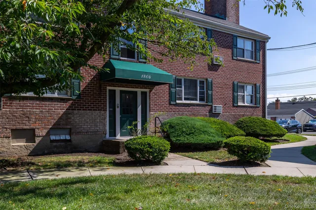 a view of a house with a yard plants and a large tree