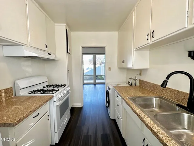 a kitchen with granite countertop a sink stove a refrigerator and cabinets