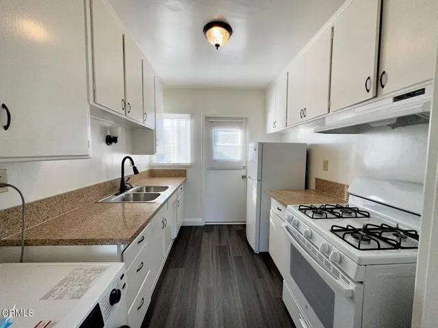 a kitchen with granite countertop a sink stove and cabinets