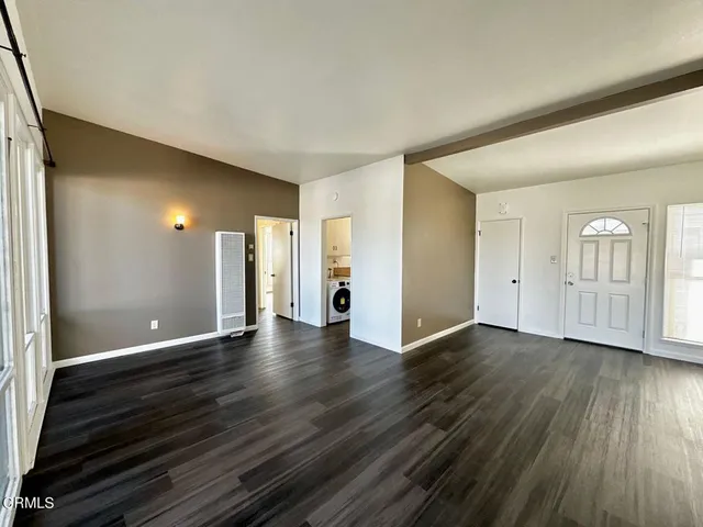 a view of an empty room with window and wooden floor