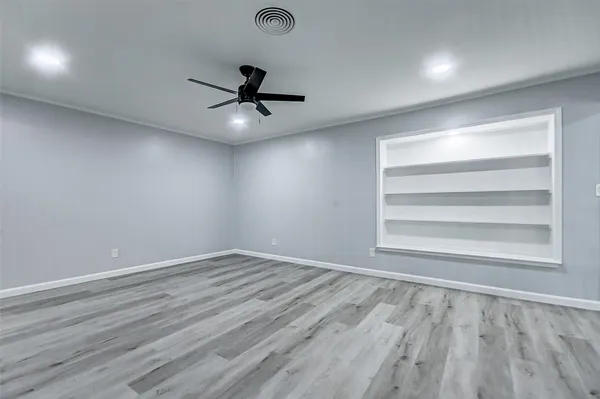 a view of an empty room with a window and wooden floor