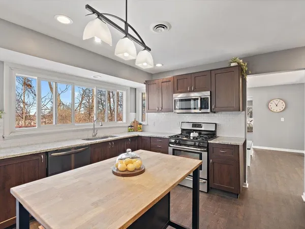 a room with granite countertop a sink dishwasher a dining table and chairs with wooden floor