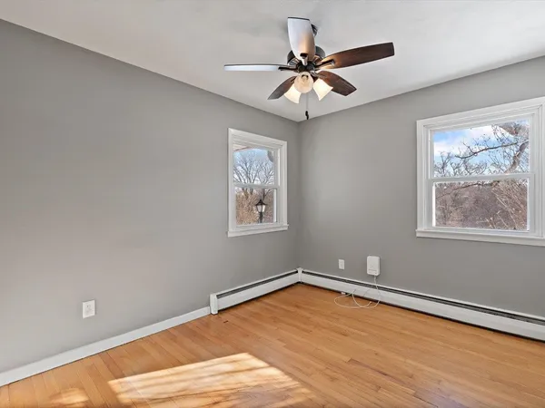 a view of an empty room with a window and wooden floor