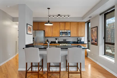 a kitchen with stainless steel appliances a dining table chairs microwave and sink