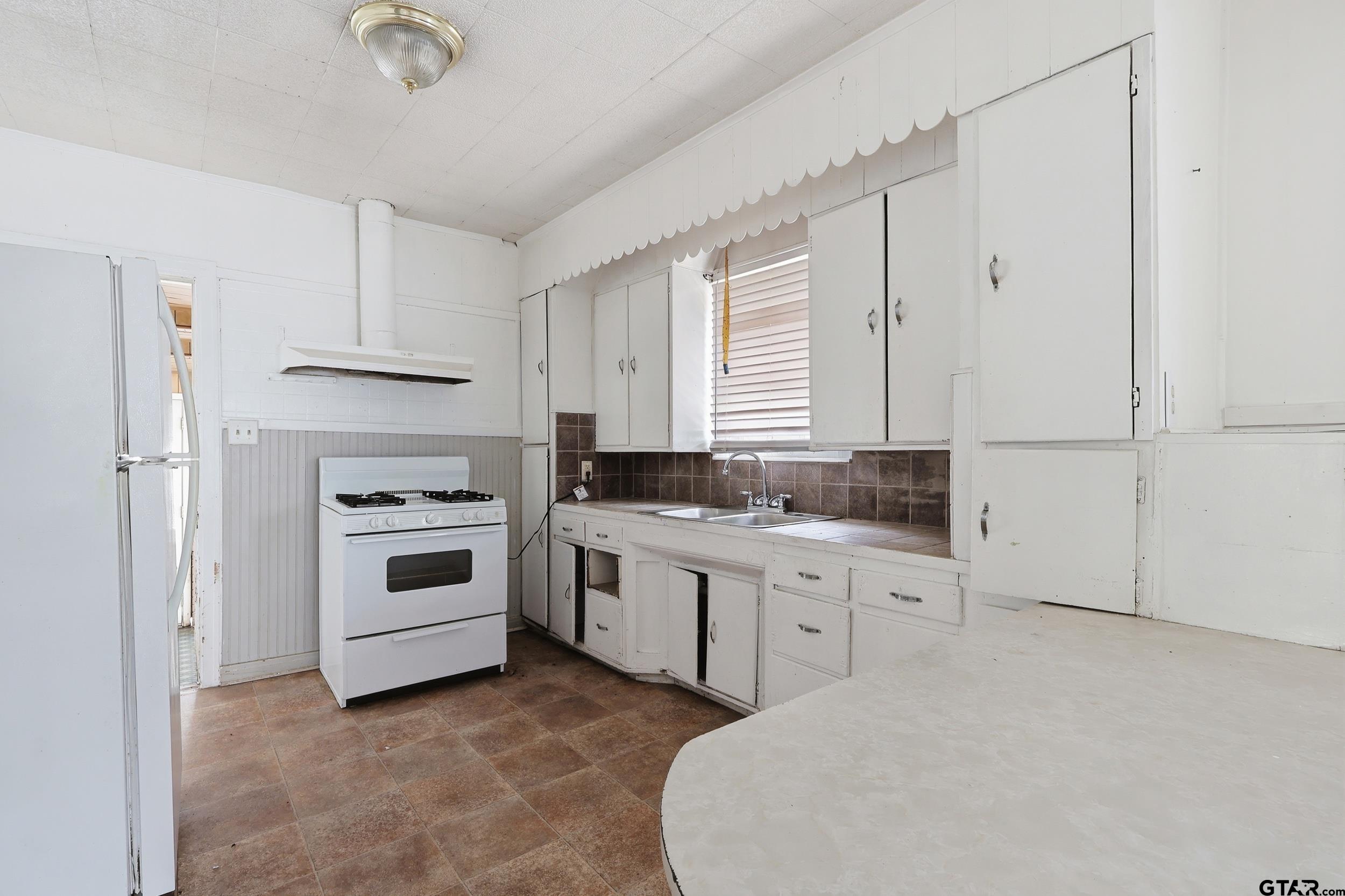 405 Rusk Street Pittsburg, TX 75686 - Photo 18 of 33 a kitchen with white cabinets and white appliances