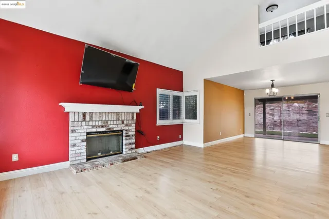 an empty room with wooden floor fireplace and windows