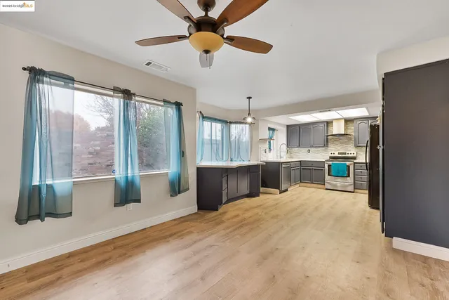 a large kitchen with kitchen island a large window cabinets stainless steel appliances and a sink