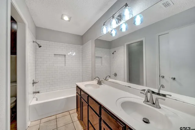 a bathroom with a tub double sink shower and mirror