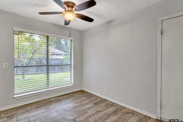 a view of an empty room with window and chandelier fan
