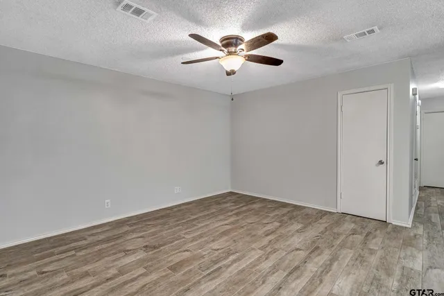 an empty room with ceiling fan and wooden floor