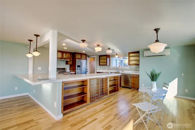 a large kitchen with stainless steel appliances a large counter top a stove and a wooden floors