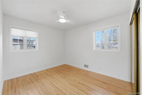 a view of empty room with wooden floor and fan
