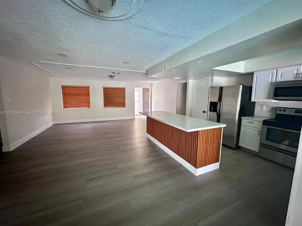 a large living room with stainless steel appliances wooden floors and a fireplace