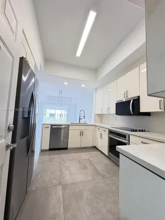a large kitchen with stainless steel appliances granite countertop a stove a sink dishwasher and a refrigerator