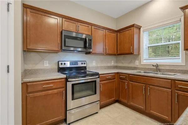 a kitchen with stainless steel appliances granite countertop white cabinets granite counter tops and a window
