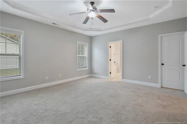 an empty room with chandelier fan and windows