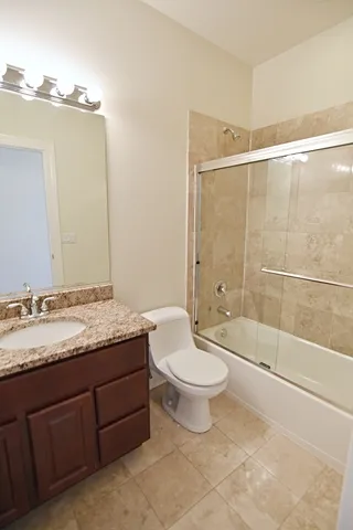 a bathroom with a granite countertop toilet a sink and a mirror