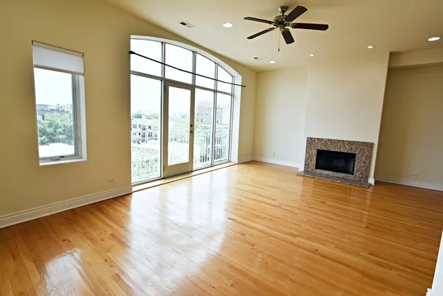 a view of an empty room with window and wooden floor