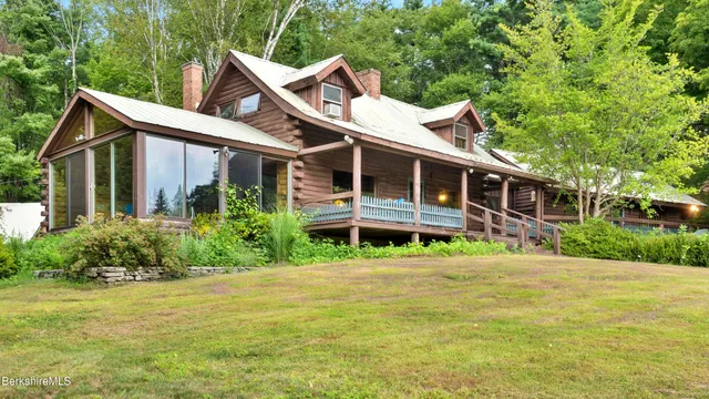a front view of a house with a yard balcony and trees