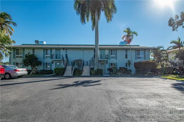 front view of house with potted plants and palm trees