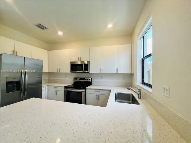 a kitchen with a sink a counter top space cabinets and stainless steel appliances