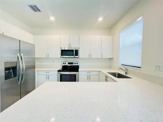a kitchen with kitchen island a sink stainless steel appliances and cabinets