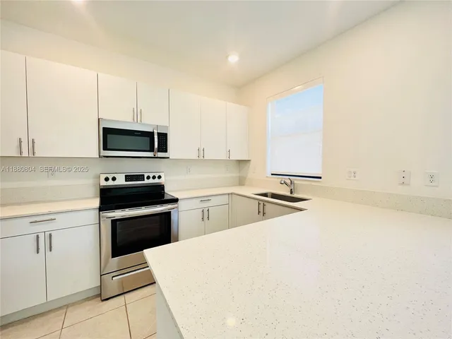a kitchen with stainless steel appliances a stove a sink a microwave and cabinets